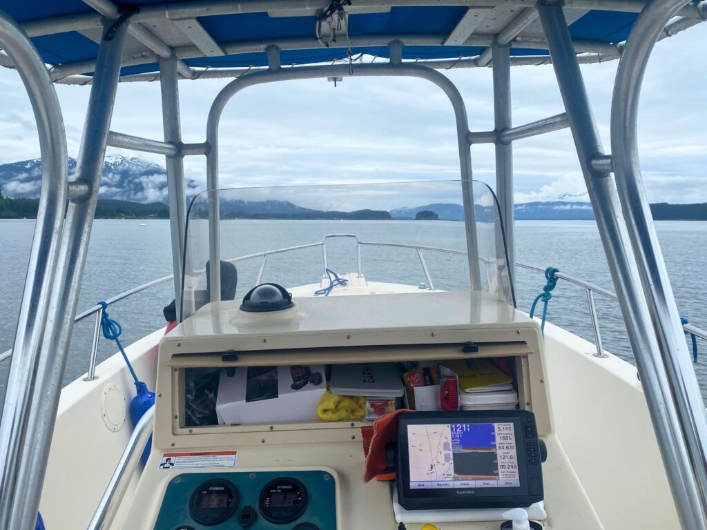 The helm of the Reel Fish boat with Garmin GPS and Yamaha engine gauges, mountains visible beyond.