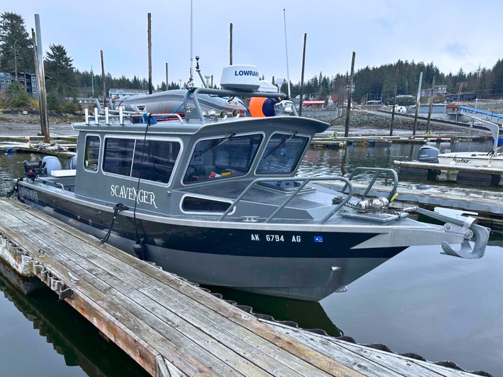 The Scavenger cabin cruiser tied up at a wooden dock in Juneau, Lowrance radar and life-saving gear visible.